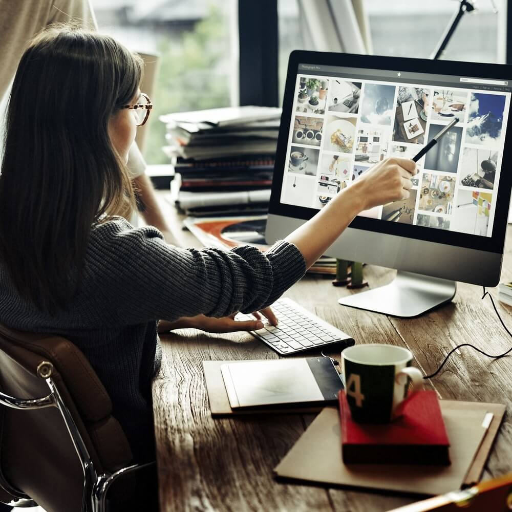 Webdesignerin zeigt mit Stift auf Bildschirm